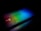 A laptop keyboard is illuminated with a spectrum of rainbow colors, including red, green, and blue tones. The colorful lighting creates a striking contrast against the dark background, enhancing the visibility of the keyboard and touchpad. The logos of AMD and Intel are visible, adding branding elements to the sleek design.