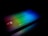 A laptop keyboard is illuminated with a spectrum of rainbow colors, including red, green, and blue tones. The colorful lighting creates a striking contrast against the dark background, enhancing the visibility of the keyboard and touchpad. The logos of AMD and Intel are visible, adding branding elements to the sleek design.