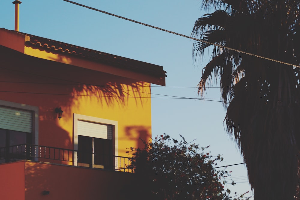 yellow concrete house beside tree