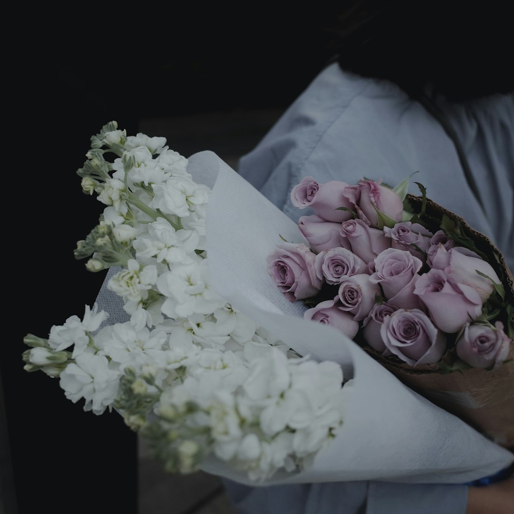 Person mit lila und weißem Blumenstrauß