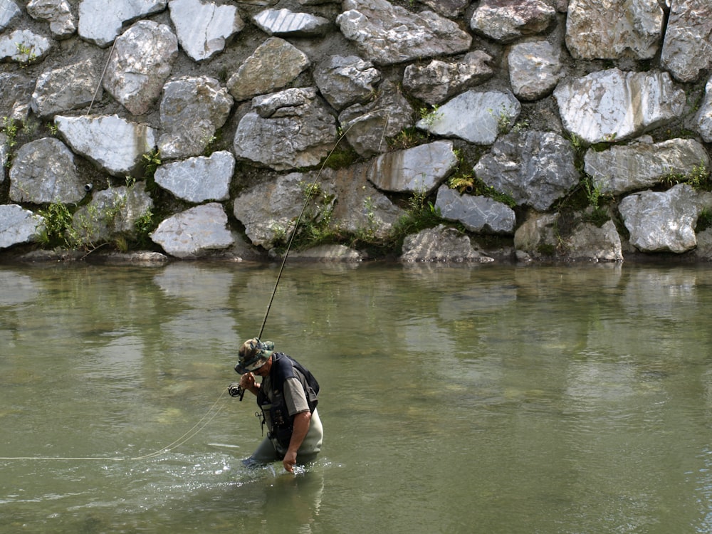 man holding fishing rod on lake