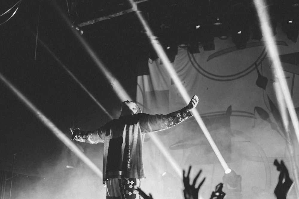 grayscale photo of man extended his arms surrounded by people