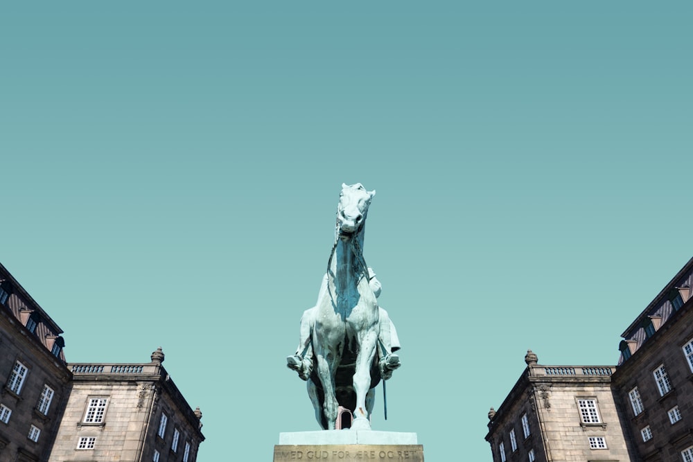 white horse statue near houses under blue sky