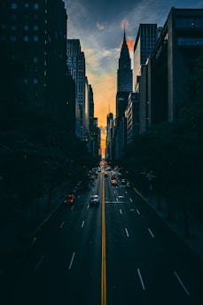 low light photography of vehicle crossing road between high-rise buildings