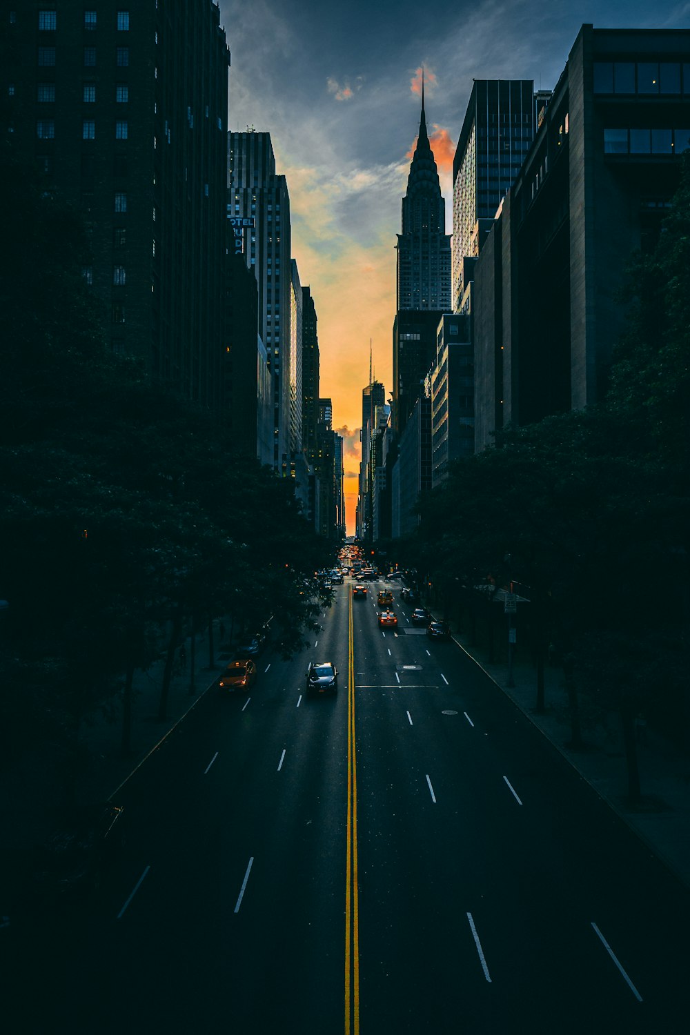 low light photography of vehicle crossing road between high-rise buildings