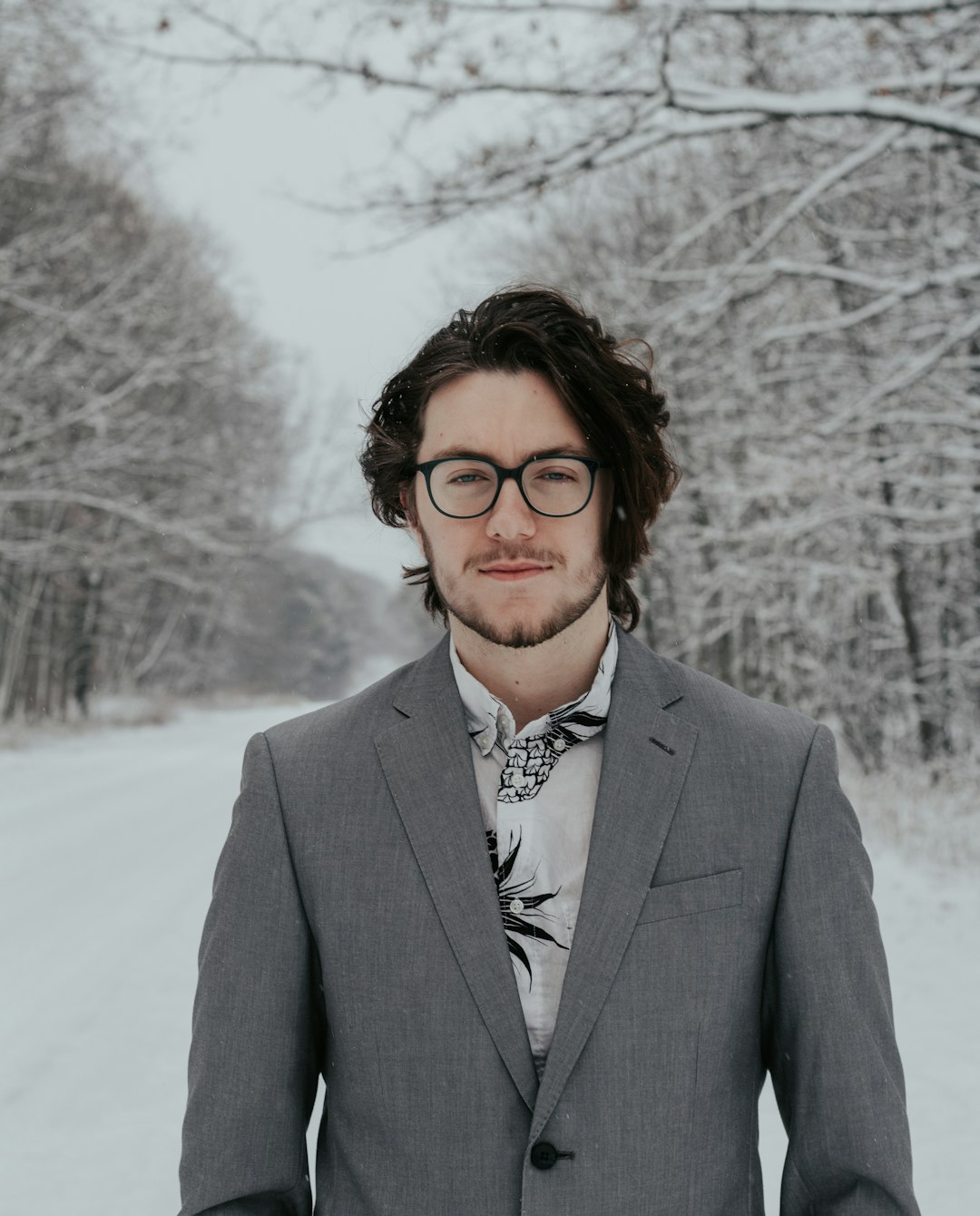 man standing near snow-capped road near tree during daytime