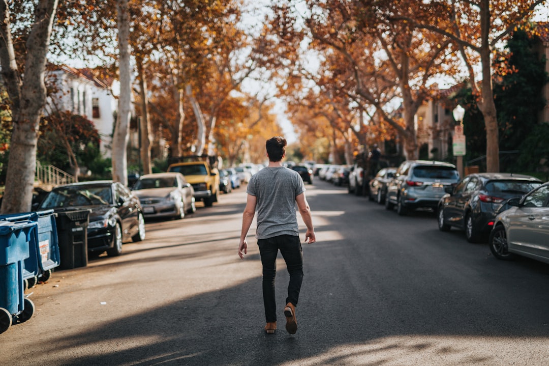 man walking on road between parked vehicles