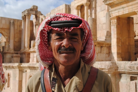close-up photo of man wearing keffiyeh behind concrete building in Jerash Governorate Jordan