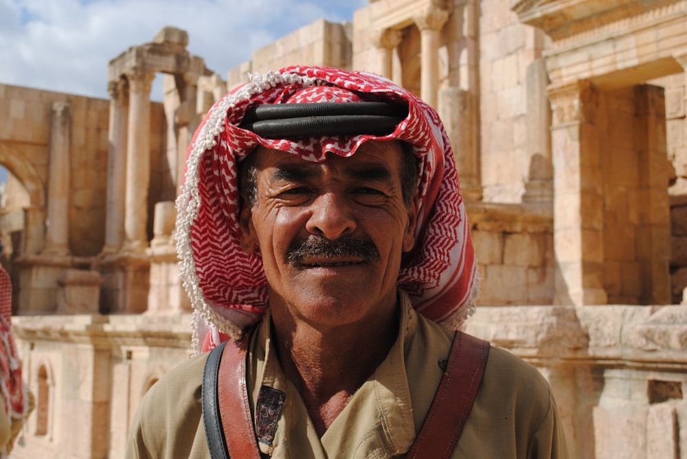 close-up photo of man wearing keffiyeh behind concrete building