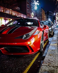 A sleek, shiny red sports car parked on a city street at sunset.