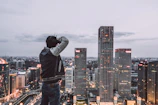 Cityscape at dusk with a male traveler capturing the skyline from a rooftop.