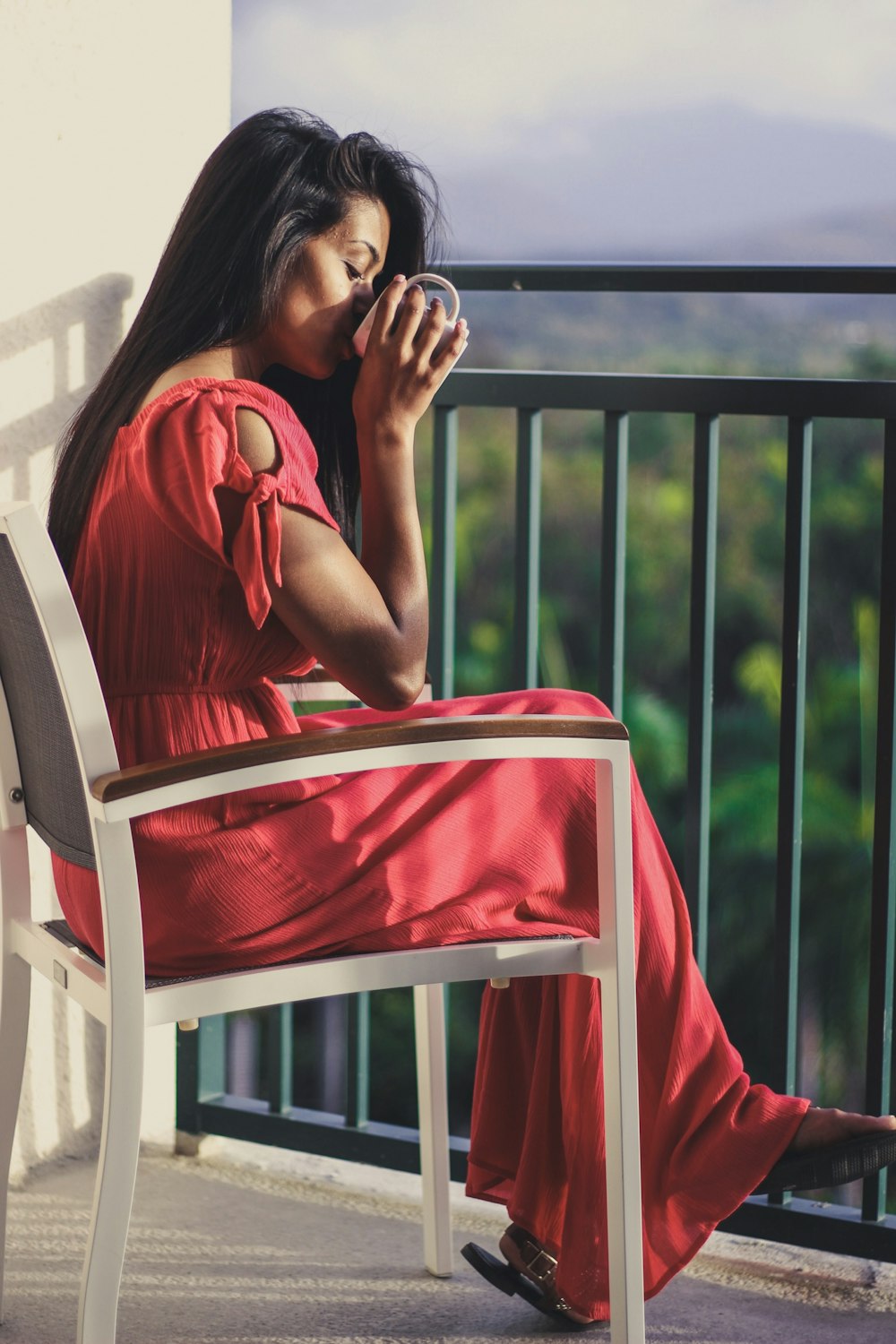 woman holding mug sitting on white armchair