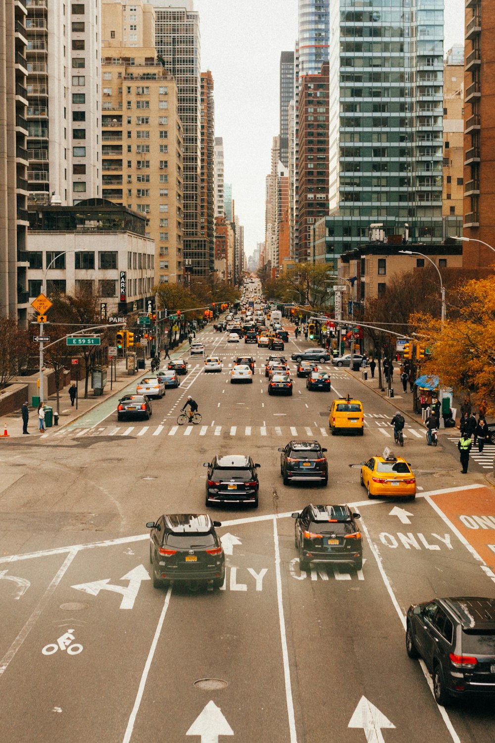 assorted vehicle passing on grey concrete road between high-rise buildings during daytime