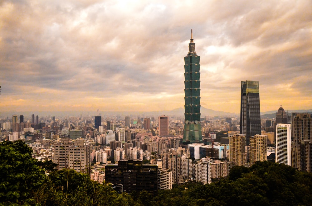 green tower building surrounded by concrete buildings