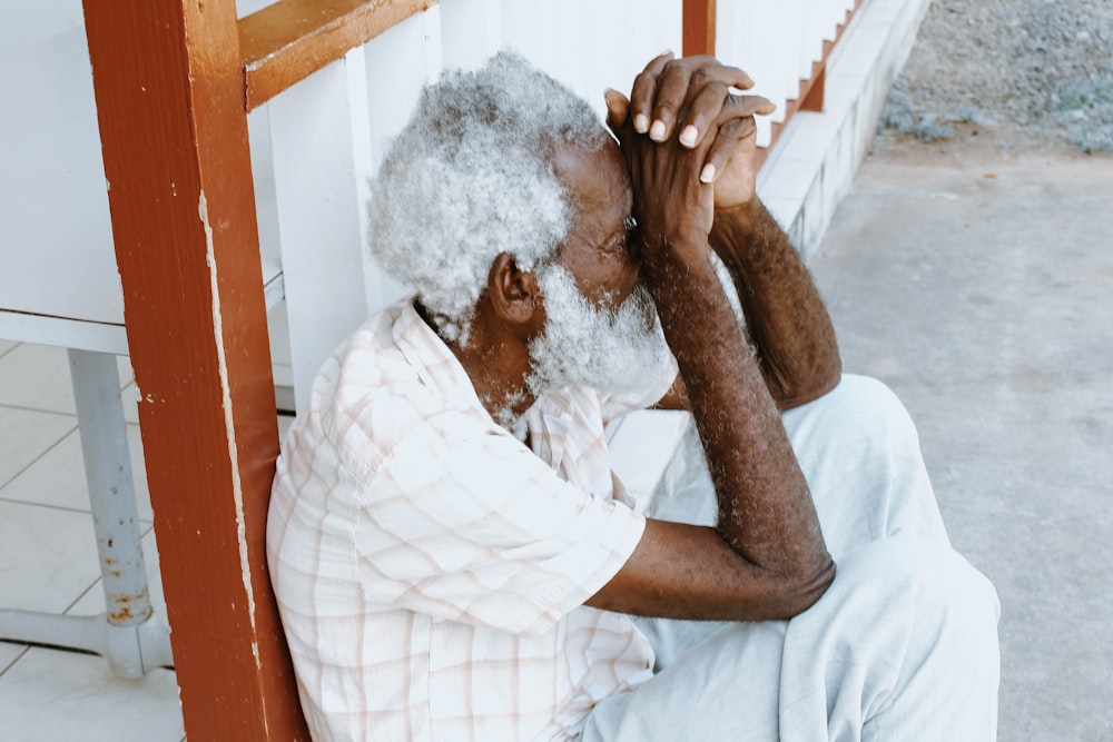 man sitting on curb leaning against balustrade at daytime