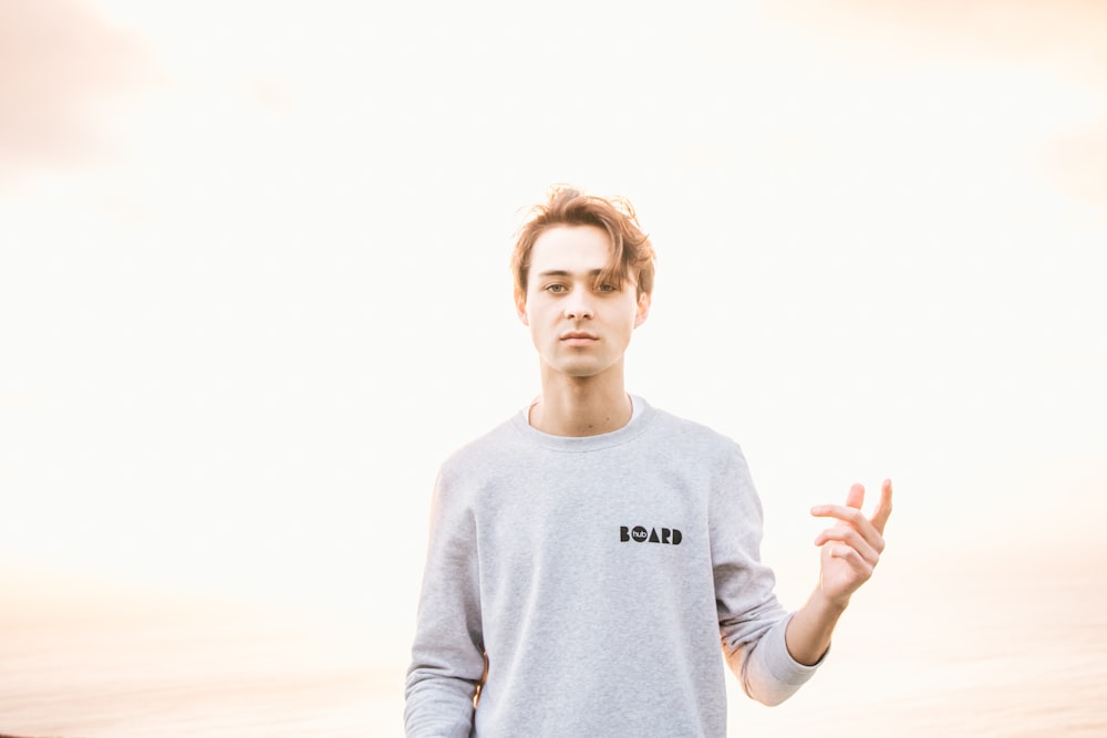 man in gray sweatshirt raising his left hand