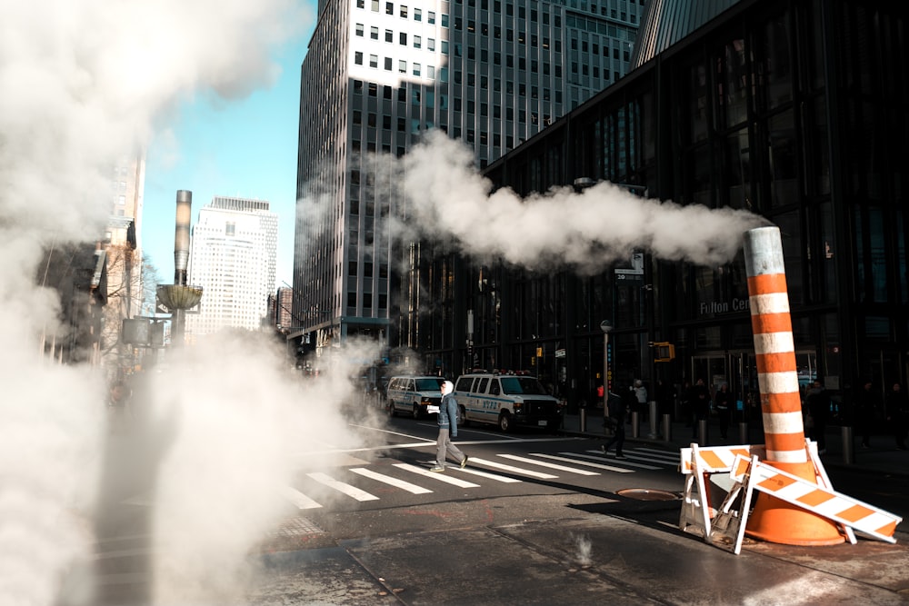 white and orange pedestal road sign with smoke beside building