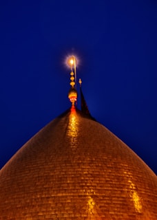 The Dome of the Rock shining at sunset, with city lights beginning to twinkle around it.