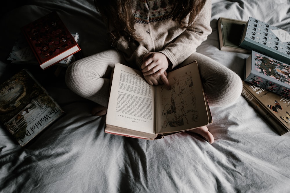 person sitting on bed reading book