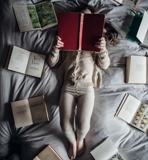 a little girl laying on a bed with lots of books