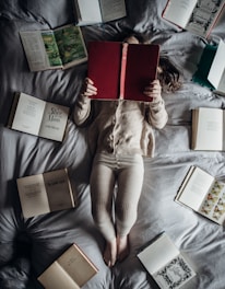 a little girl laying on a bed with lots of books