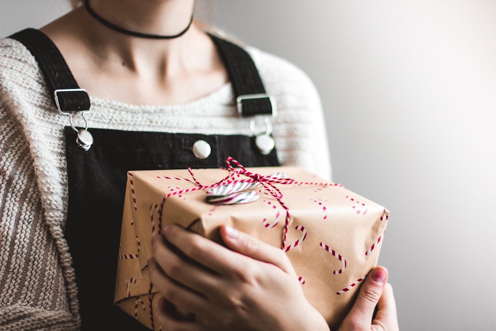 close up photography of woman holding grey and red box