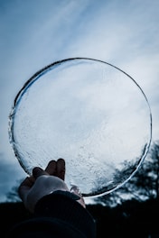 person holding round clear ice glass