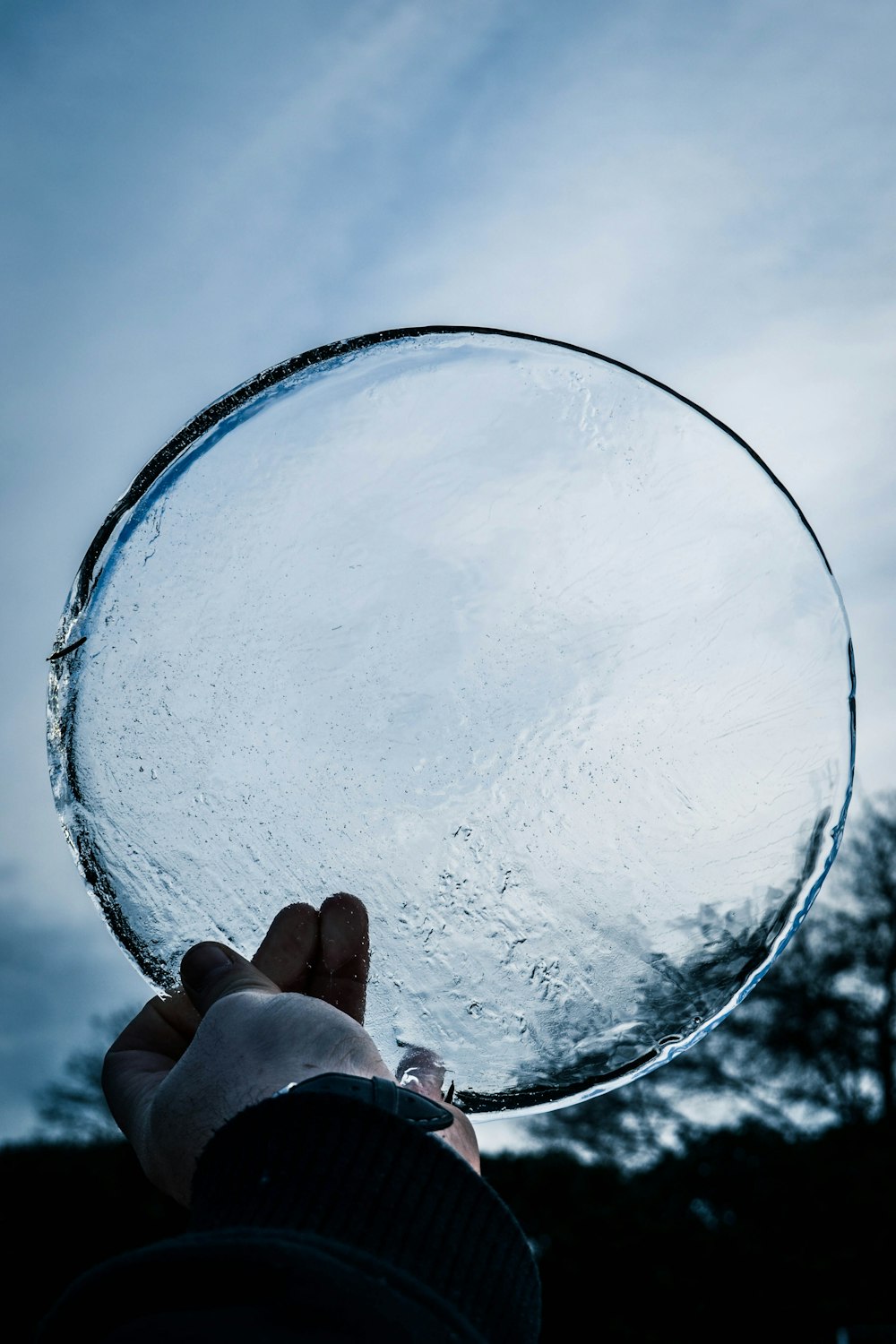 person holding round clear ice glass