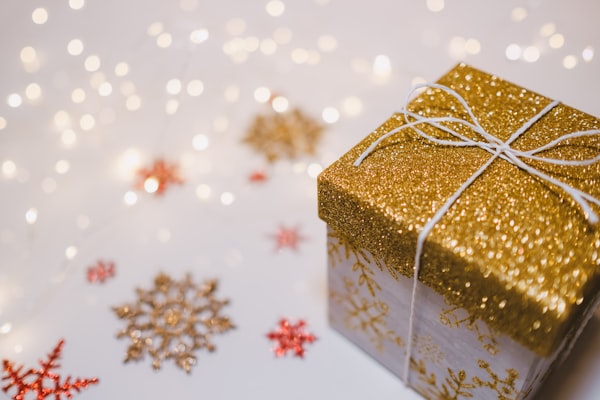 White background with sparkles, gold and red snowflake decorations and boxed shape present with gold lid