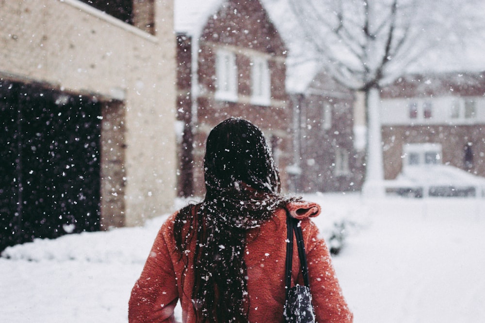 selective focus photography of woman wearing red coat standing in front of building