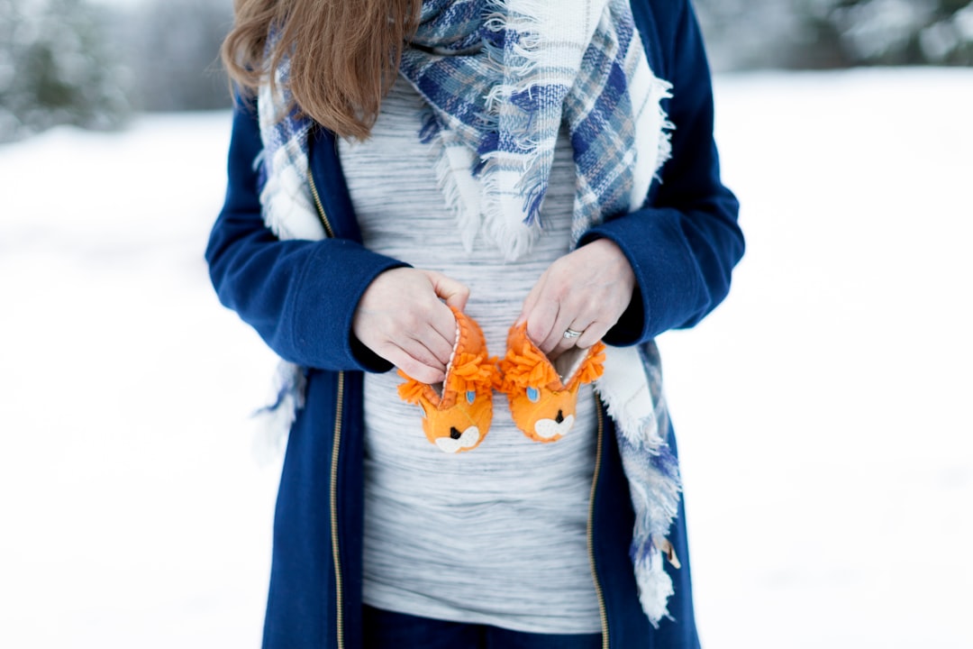 woman holding baby's orange animal shoes