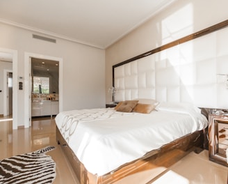 brown wooden bed frame with white cover beside brown wooden nightstand