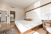 brown wooden bed frame with white cover beside brown wooden nightstand
