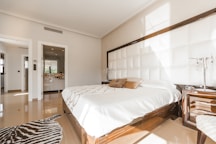 brown wooden bed frame with white cover beside brown wooden nightstand