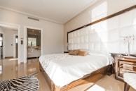 brown wooden bed frame with white cover beside brown wooden nightstand