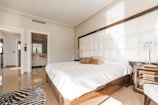 brown wooden bed frame with white cover beside brown wooden nightstand