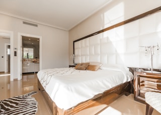 brown wooden bed frame with white cover beside brown wooden nightstand