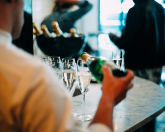 person wearing shirt shirt holding wine bottle pouring on glass during daytime photography