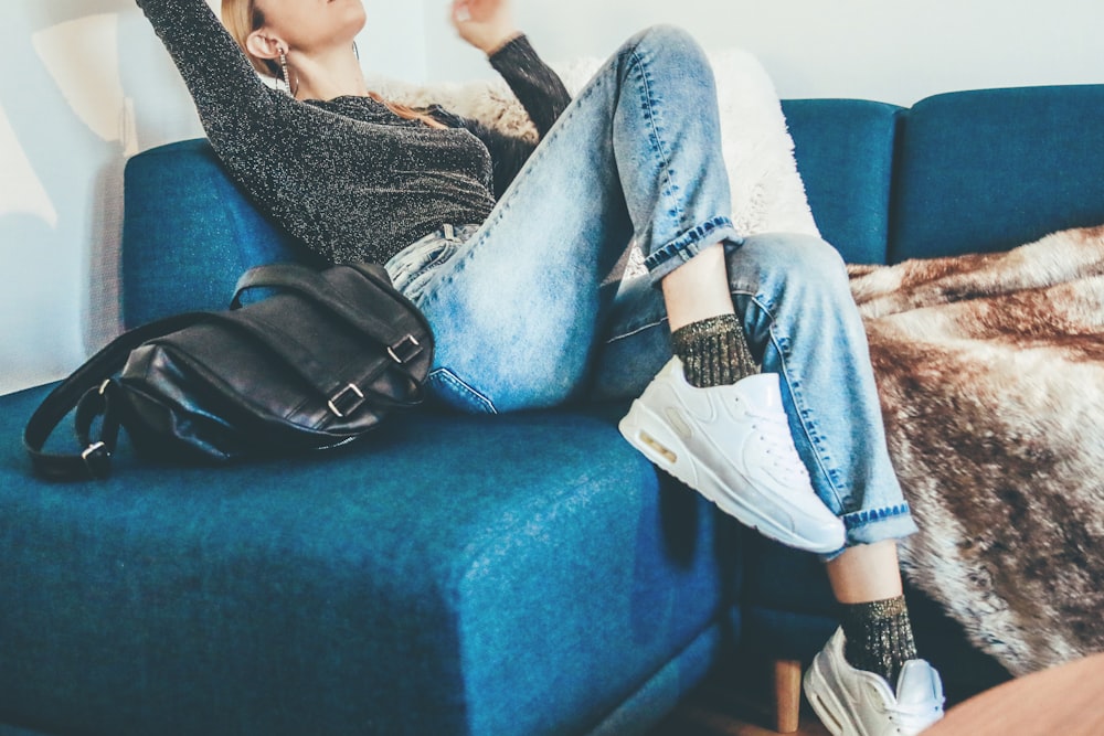 woman sitting on sofa beside bag