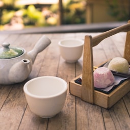 white ceramic mug near tea pot on table