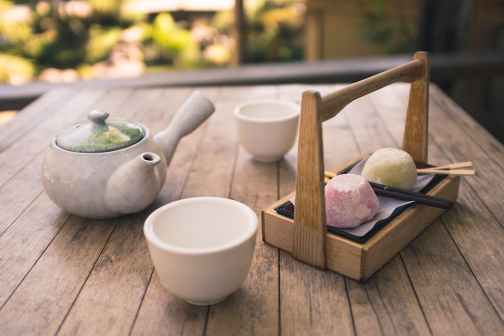 white ceramic mug near tea pot on table