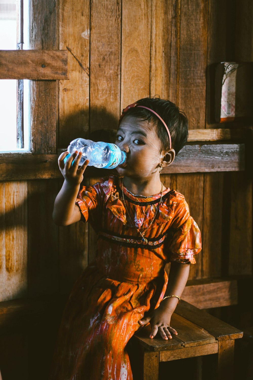 toddler sitting on stool chair while drinking water