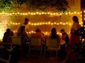 A group enjoying a meal around a unique roofdeck dining table under string lights.