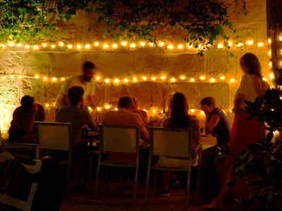 A cozy backyard gathering with string lights and happy friends sharing laughs around a table.