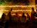 Guests laughing around a beautifully arranged outdoor dining table under string lights at dusk.