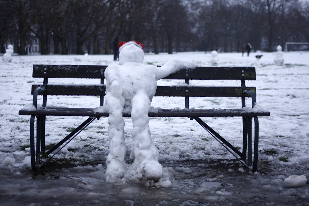 bonhomme de neige sur banc en bois noir pendant la journée