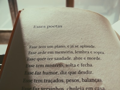 The image features an open book with a page of Portuguese text. The title reads 'Esses poetas,' followed by several poetic lines. The lighting is warm and casts a soft shadow on the page, suggesting early morning or late afternoon sunlight.