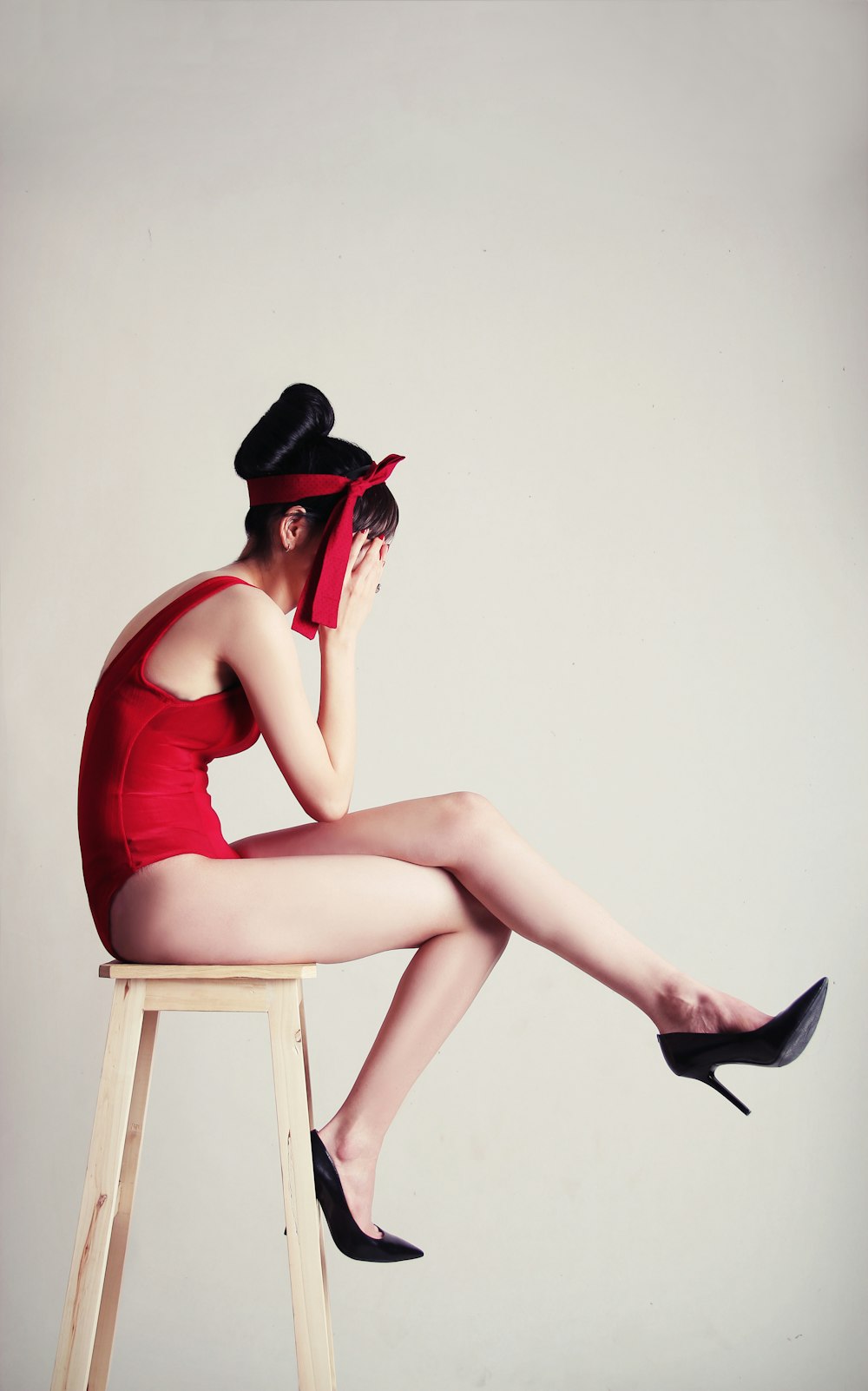 upset woman sitting on stool with white background