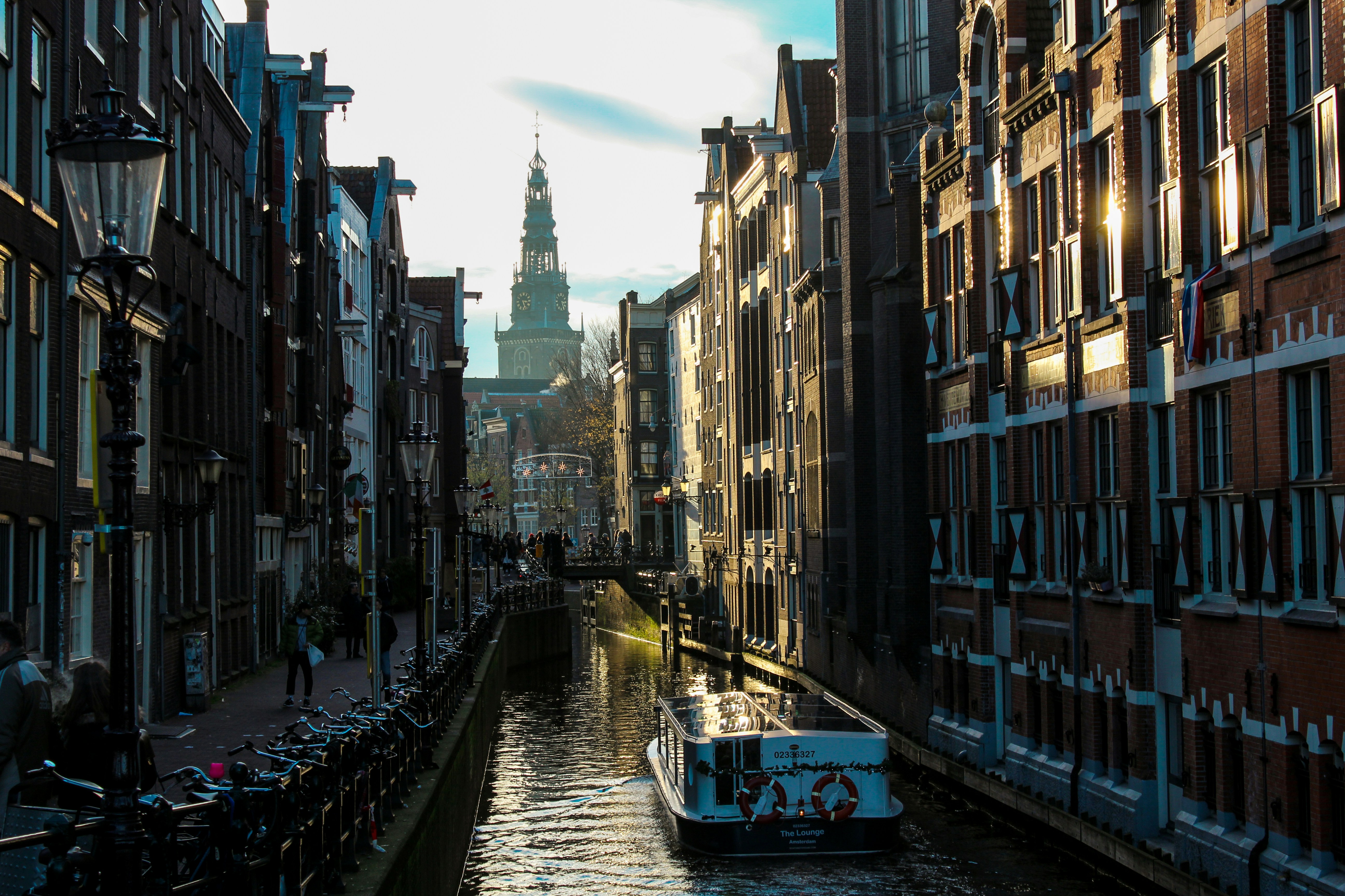 white boat in between high-rise buildings under white and blue skies at daytime, Afternoon, 4 or 5 PM - Amsterdam, The Netherlands.</p><p>I had been walking for 5 hours through Amsterdam, looking for the perfect shot. Weather wasn’t working for me, cold and grey. Then when I crossed a bridge, I saw the touring boat EVERY tourist takes and knew I needed to get a good shot in. Combination of the touring boat + the city guided tour on the bridge opposite + the typical Dutch architecture makes me feel at home. I love Amsterdam.