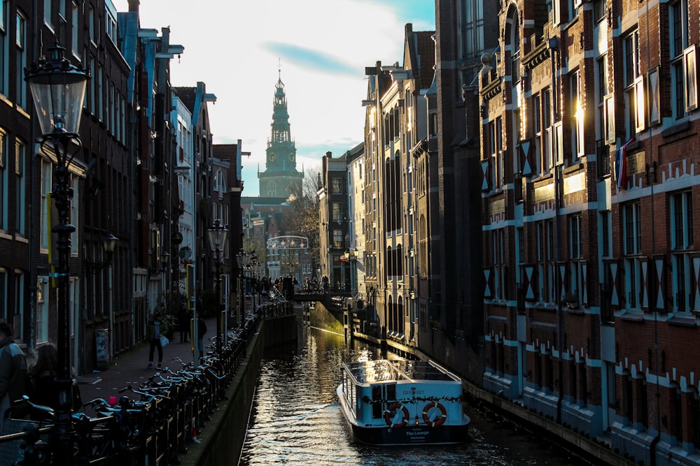 white boat in between high-rise buildings under white and blue skies at daytime